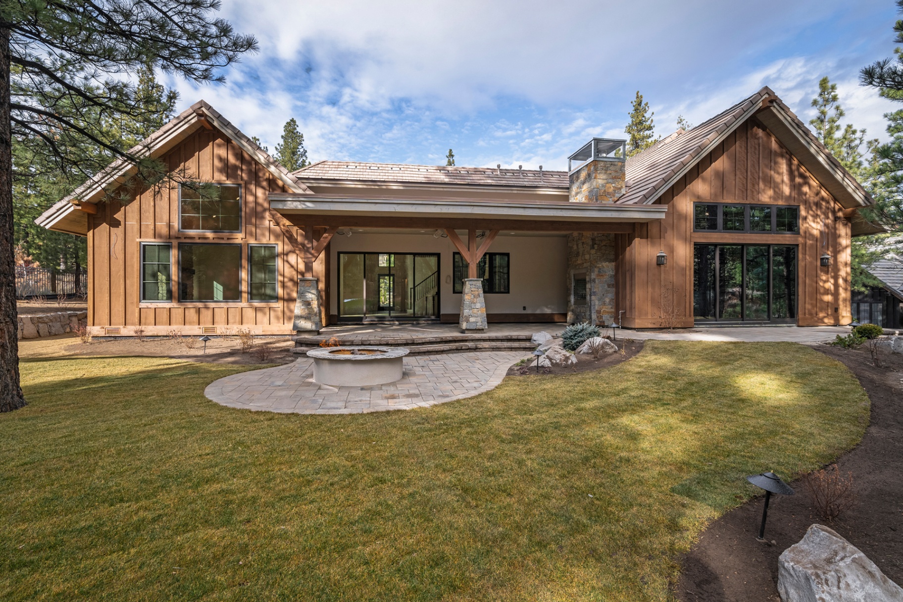 Rear exterior with covered patio, stone fire pit, and manicured lawn